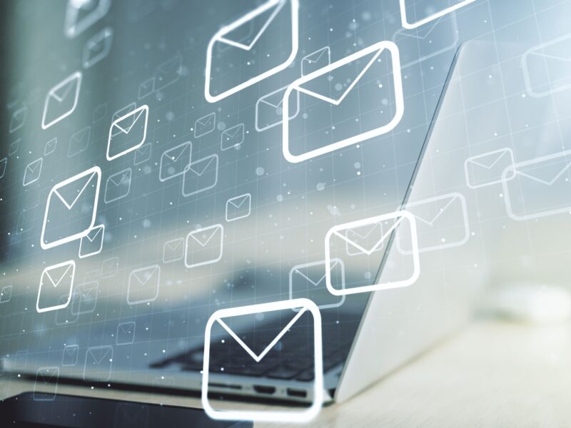 Laptop screen overlaid with floating email envelope icons, investment newsletters